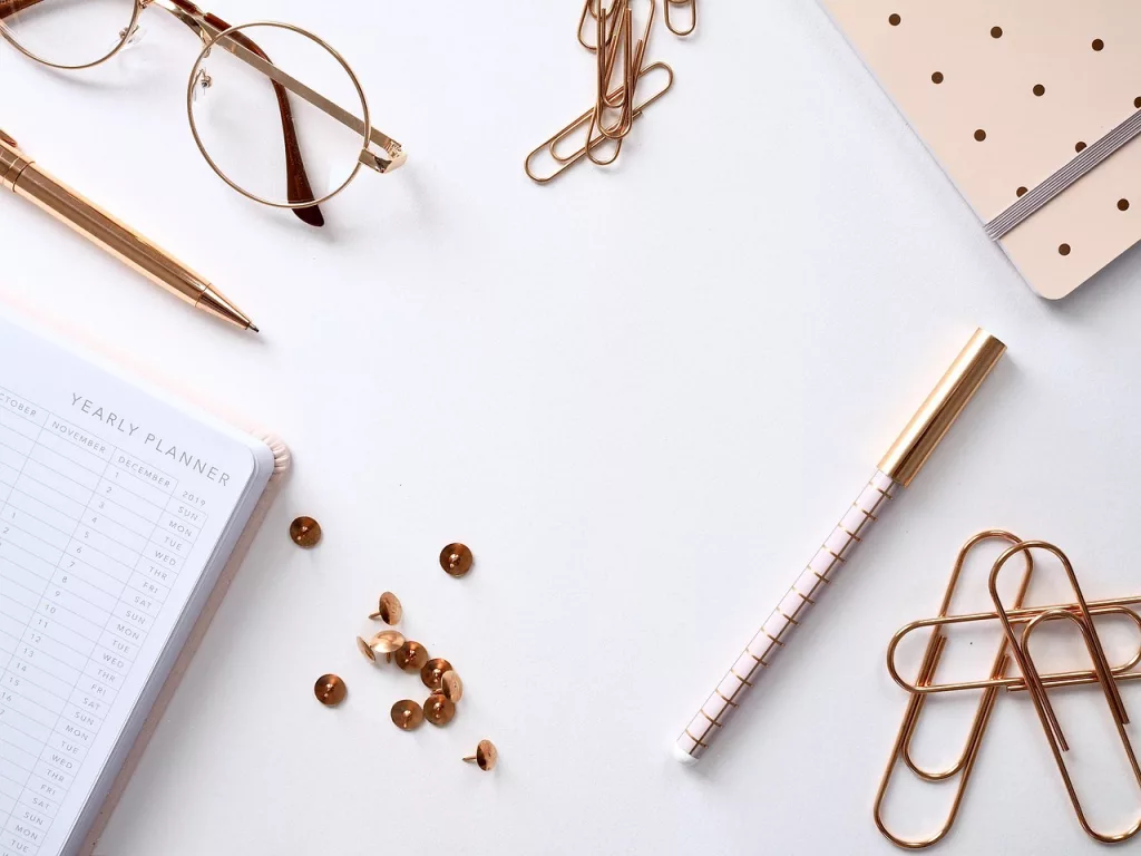 A bright rose gold desk flat lay with a yearly planner for budgeting abroad